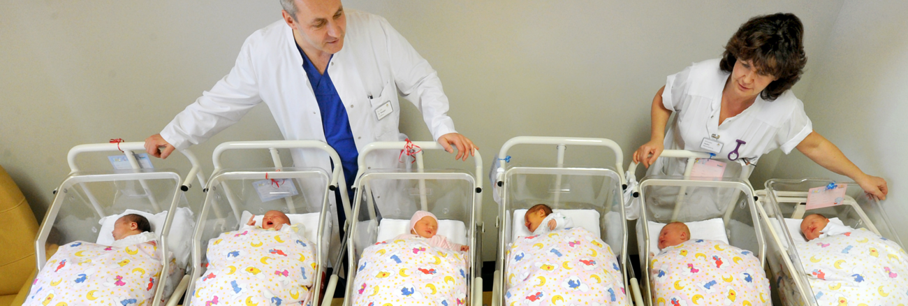 Ein Arzt und eine Krankenschwester hinter zwei Reihen Betten mit Babys in der Neugeborenenstation in einem Krankenhaus in Halle © picture alliance/ZB/Waltraud Grubitzsch