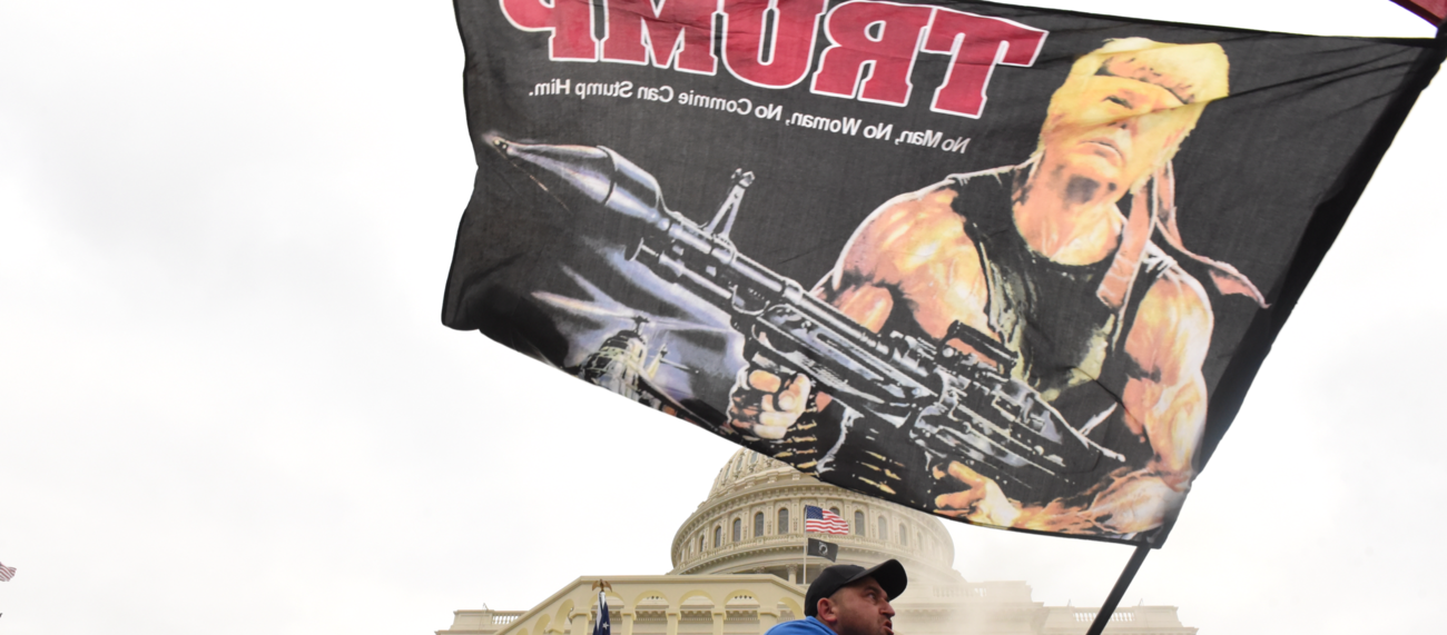Beim Sturm auf das Kapitol am 7. Januar 2021 in Washington trägt ein Trump-Anhänger eine Fahne, die Trump als Rambo mit Panzerfaust zeigt © REUTERS/Stephanie Keith