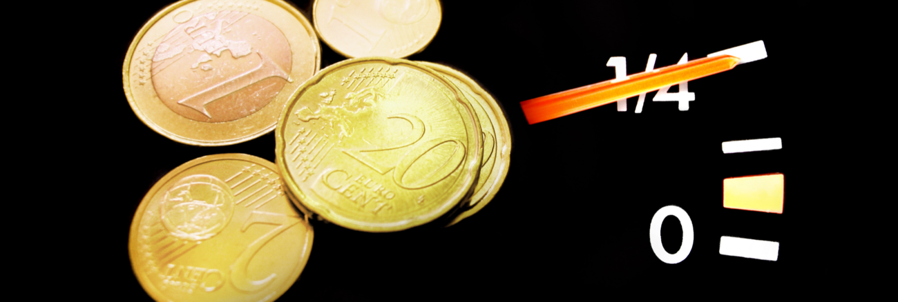 Euromünzen neben einer Tankanzeige mit dem Zeiger auf Einviertel © iStock/deepblue4you