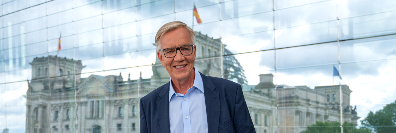 Dietmar Bartsch vor einer Glaswand, in der sich der Reichstag spiegelt © picture alliance/dpa | Christophe Gateau