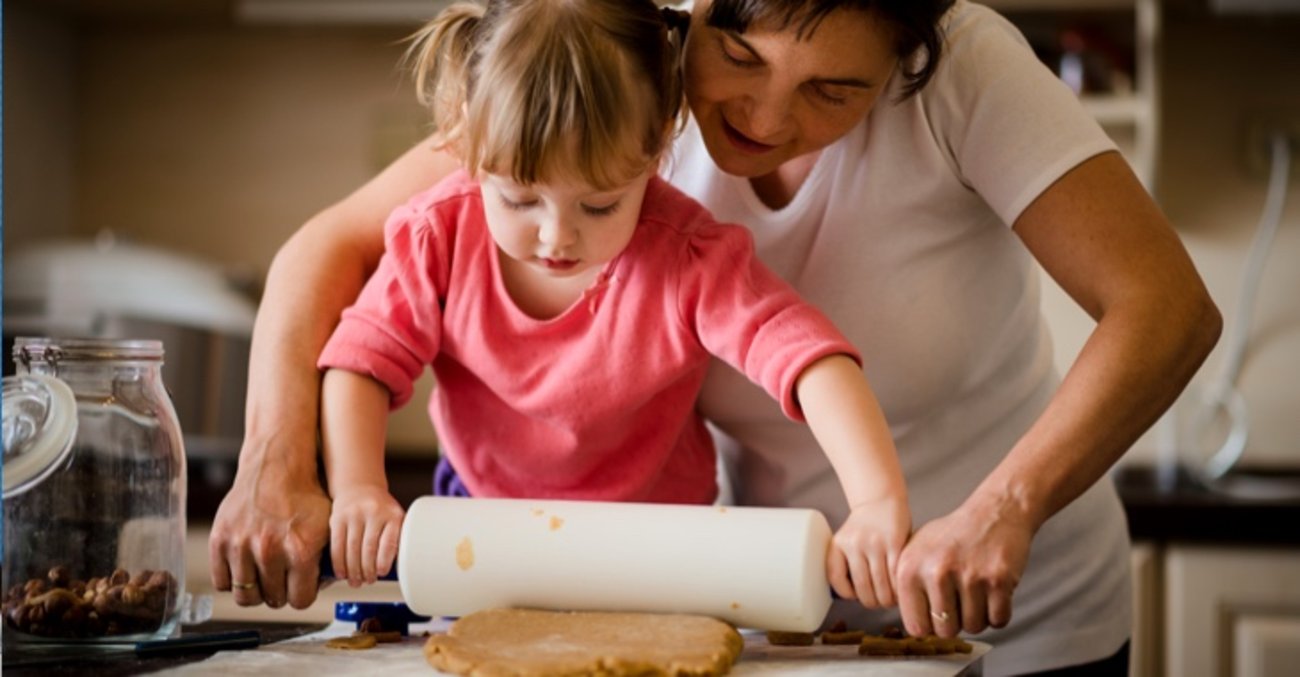 Mutter und Tochter rollen mit einem Nudelholz Kuchenteig aus © iStock/Martinan