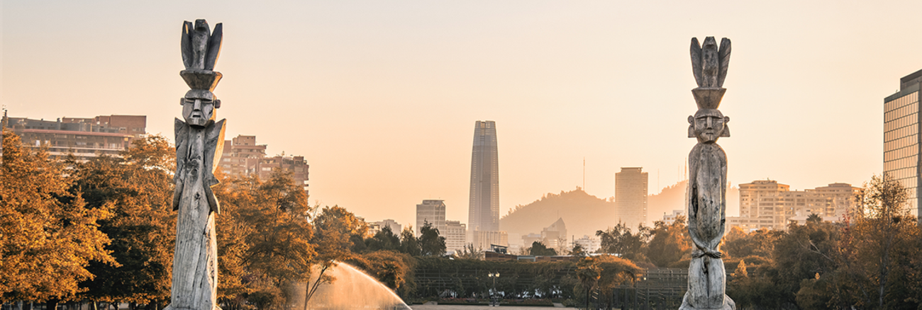 Traditionelle Statuen des indigenen Stammes Mapuche mit Skyline von Santiago, Chile, im Hintergrund 