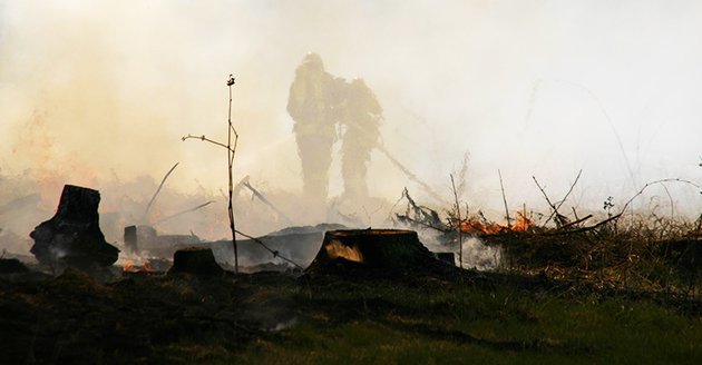 Zwei Feuerwehrleute bei Löscharbeiten in den Rauchschwaden eines Waldbrandes. Foto: Flickr.com/free-skier (CC BY-NC-SA 2.0)