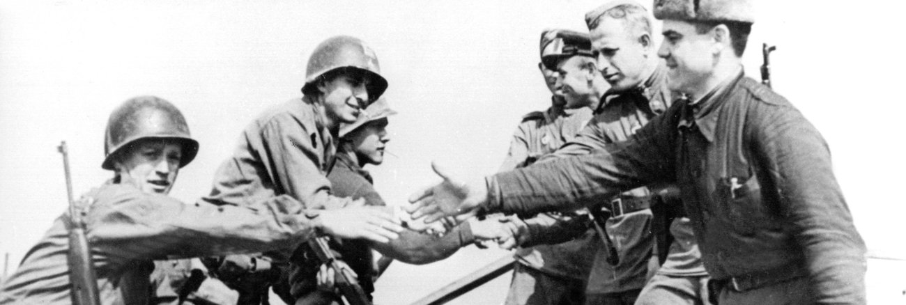 Sowjetische und US-amerikanische Soldaten reichen sich im April 1945 auf den Trümmern einer Elbbrücke bei Torgau die Hände @ dpa