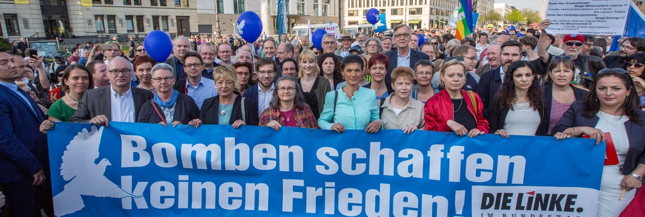 Bei der Friedenskundgebung am 18. APril 2018 am Brandenburger Tor in Berlin für Deeskalation in Syrien halten Mitglieder der Linksfraktion ein Transparent mit der Aufschrift: Bomben schaffen keinen Frieden!