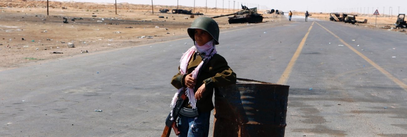 Kindersoldaten: Ein zehnjähriger Junge mit Gewehr und Helm in Libyen © REUTERS/Yannis Behrakis