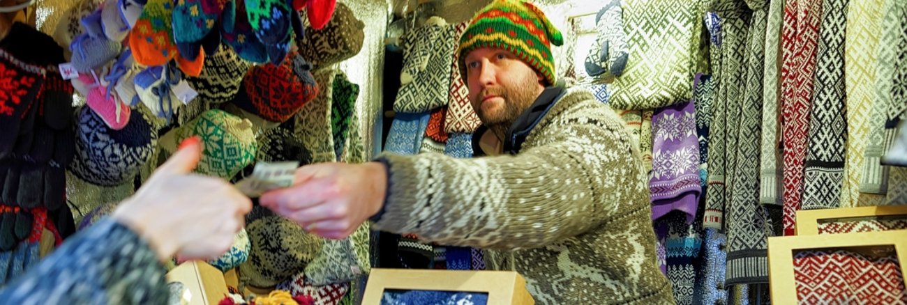 Marktverkäufer mit Strickwaren reicht einer Frau einen Euro-Schein © iStockphoto.com/Roman Babakin