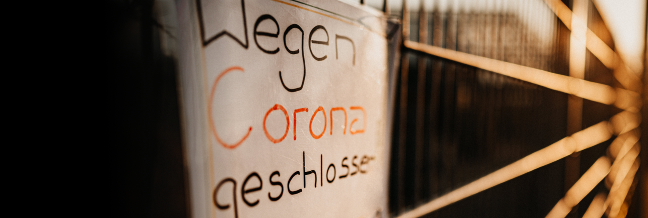 An einem Zaun ist ein Schild mit der Aufschrift »Wegen Corona geschlossen« angebracht © iStock/Danny Schoening