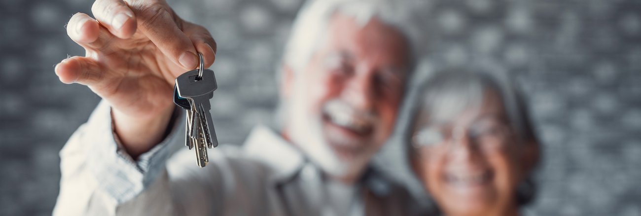 Ein älterer Mann umarmt eine Frau und hält ein Schlüsselbund © iStock/Fabio Camandona Ein älterer Mann umarmt eine Frau und hält ein Schlüsselbund © iStock/Fabio Camandona
