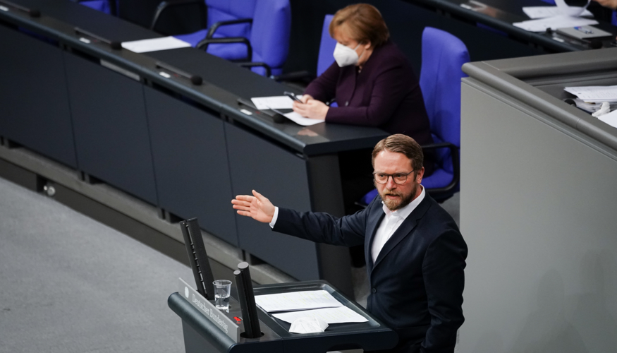 Jan Korte am Rednerpult des Bundestages, dahinter Bundeskanzlerin Merkel auf der Regierungsbank Jan Korte am Rednerpult des Bundestages, dahinter Bundeskanzlerin Merkel auf der Regierungsbank