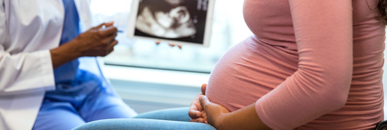 Eine Hebamme und eine Schwangere mit einer Ultraschall-Aufnahme eines Babys © iStock/SDI Productions