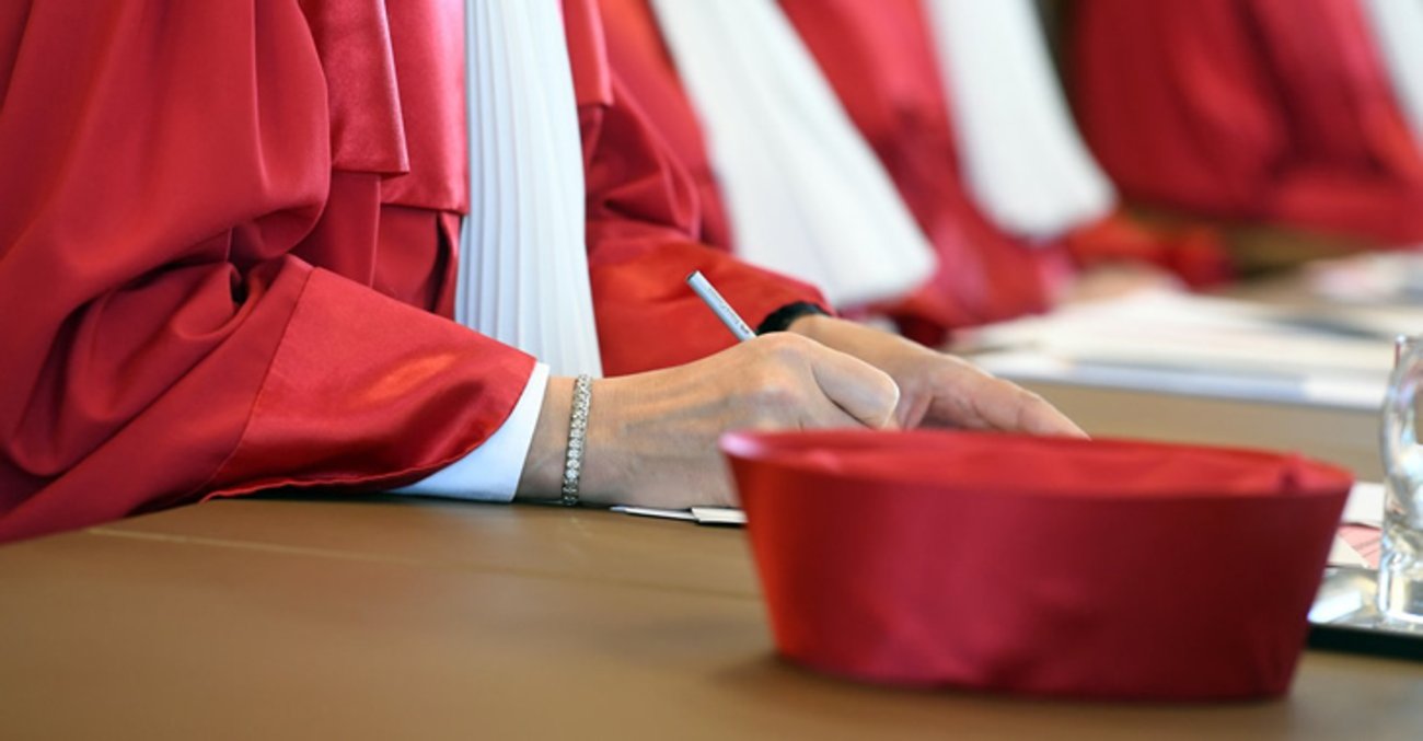 Eine rote Mütze liegt auf dem Pult neben einer Bundesverfassungsrichterin in roter Robe © dpa