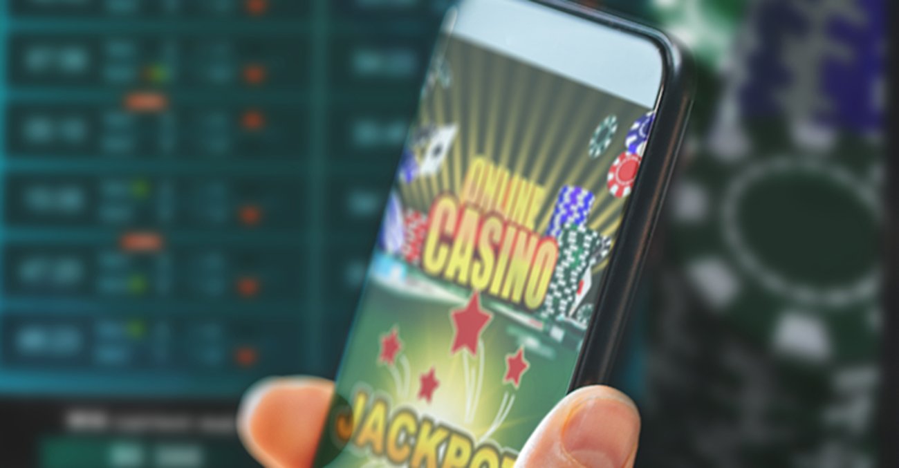 Eine Hand hält ein Handy mit einer Onlinecasino-App darauf 