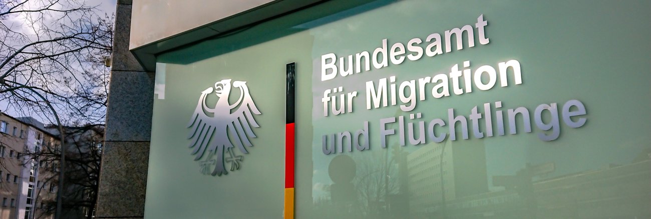 Schild mit Bundesadler und der Aufschrift Bundesamt für Migration und Flüchtlinge © iStock/princigalli