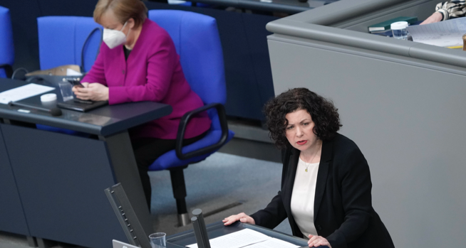 Amira Mohamed Ali am Rednerpult des Bundestages, dahinter Bundeskanzlerin Merkel auf der Regierungsbank schaut auf ihr Handy © picture alliance/Flashpic/Jens Krick Amira Mohamed Ali am Rednerpult des Bundestages, dahinter Bundeskanzlerin Merkel auf der Regierungsbank schaut auf ihr Handy © picture alliance/Flashpic/Jens Krick