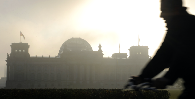 Silhouette eines Fahrradfahrers vor dem Reichstagsgebäude in Morgendunst mit dahinter aufgehender Sonne © picture-alliance/dpa/Rainer Jensen Silhouette eines Fahrradfahrers vor dem Reichstagsgebäude in Morgendunst mit dahinter aufgehender Sonne © picture-alliance/dpa/Rainer Jensen