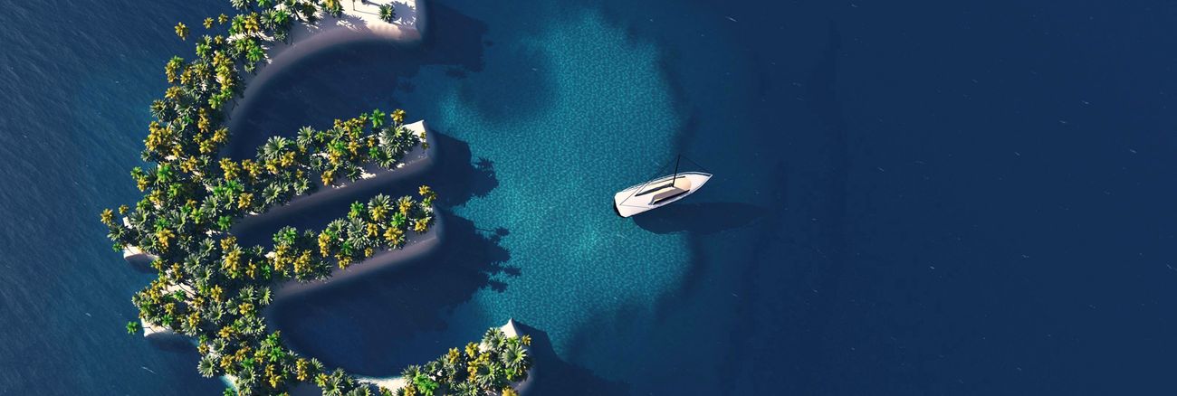 Eine Yacht schwimmt im Meer vor einer Insel in Form eines Euro-Symbols © iStock/Mihai Maxim