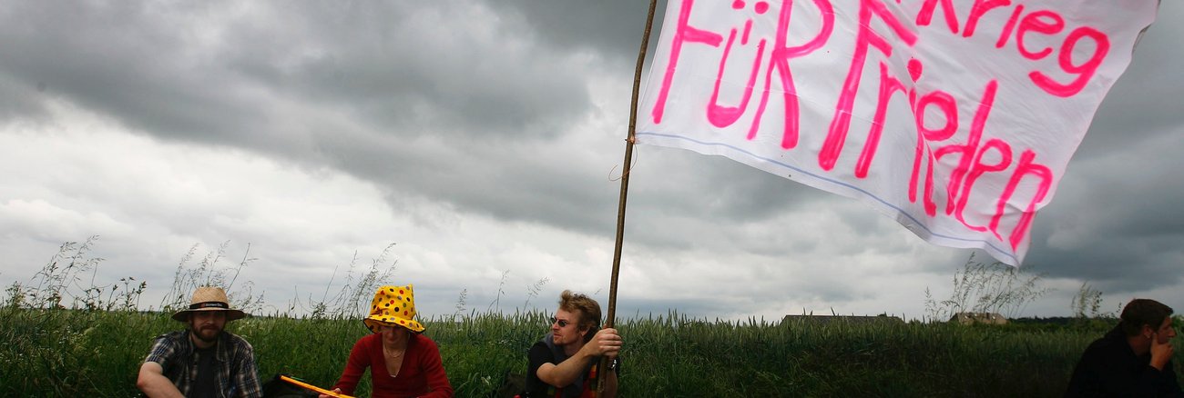 Aktivisten halten eine selbstgemalte Fahne mit der Aufschrift: Gegen Krieg Für Frieden © REUTERS/Kai Pfaffenbach