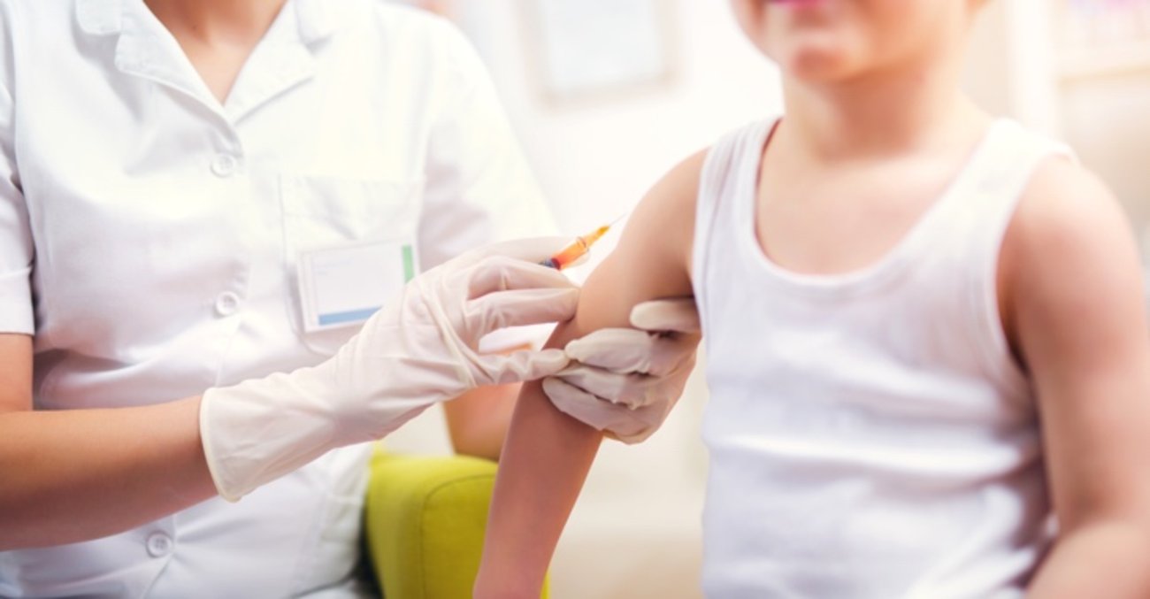 Impfung: Eine Krankenschwester gibt einem Junge eine Spritze in den rechten Oberarm © iStock/Jovanmandic