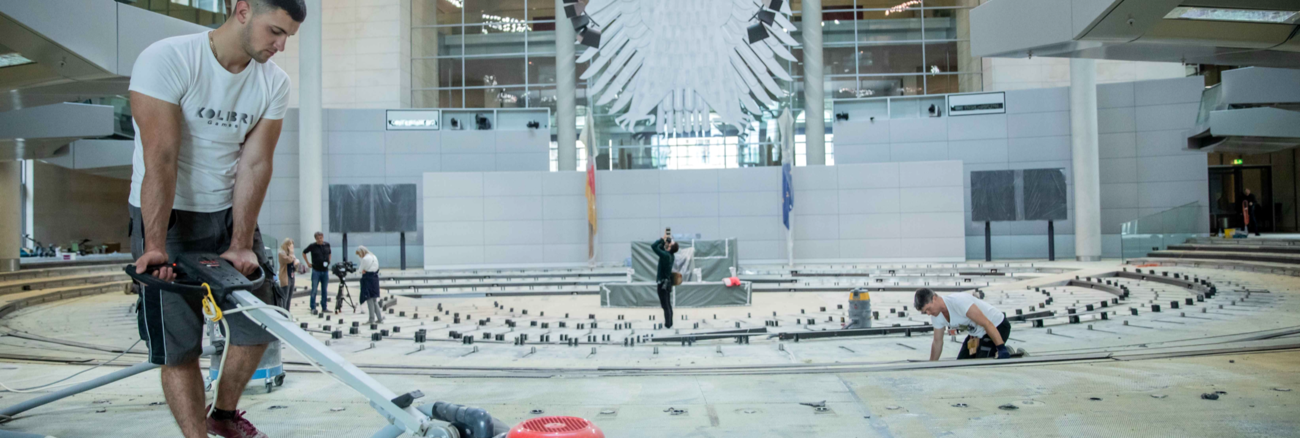 Arbeiter im leeren Plenarsaal des Bundestages mit abmontierten Sitzreihen © picture alliance/dpa/Michael Kappeler