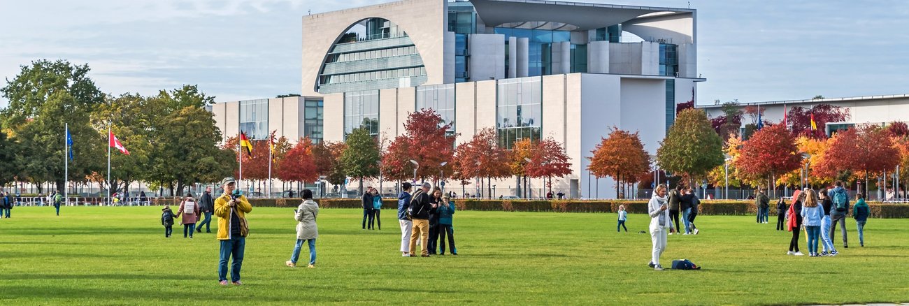 Menschen vor dem Bundeskanzleramt auf der Wiese des Platzes der Republik © iStock/laranik Menschen vor dem Bundeskanzleramt auf der Wiese des Platzes der Republik © iStock/laranik