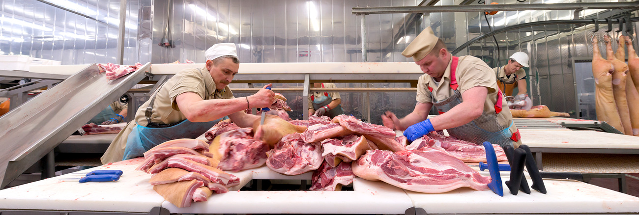 Arbeiter zerteilen Fleisch in einer Fleischfabrik / einem Schlachthof. Foto: © istock.com/IP Galanternik D.U.