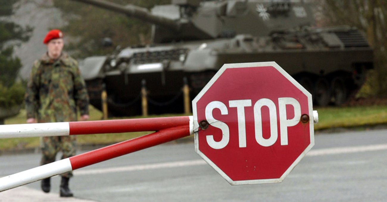 Ein Panzer und ein Soldat der Bundeswehr stehen hinter einer heruntergelassenen Schranke mit Stop-Schild © dpa