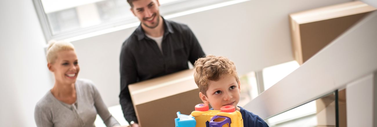 Junge Familie beim Umzug in eine neue Wohnung - Eltern mit ihrem Sohn mit Kisten auf einer Treppe © iStock/Predrag Vuckovic