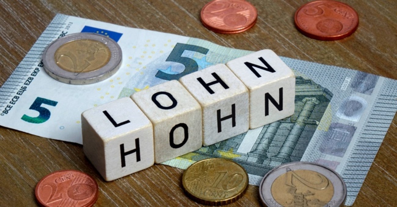 Auf einem Fünf-Euro-Schein stehen Würfel mit den Worten Lohn und Hohn © picture alliance/dpa-Zentralbild
