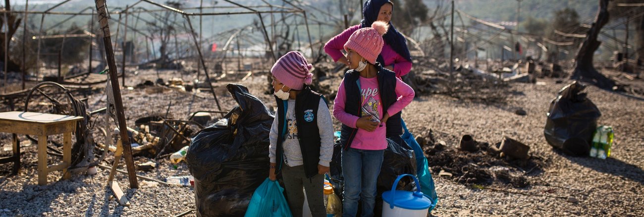Eine Mutter mit zwei Kindern 2020 vor dem ausgebrannten Flüchtlingslager Moria © picture alliance/dpa|Socrates Baltagiannis