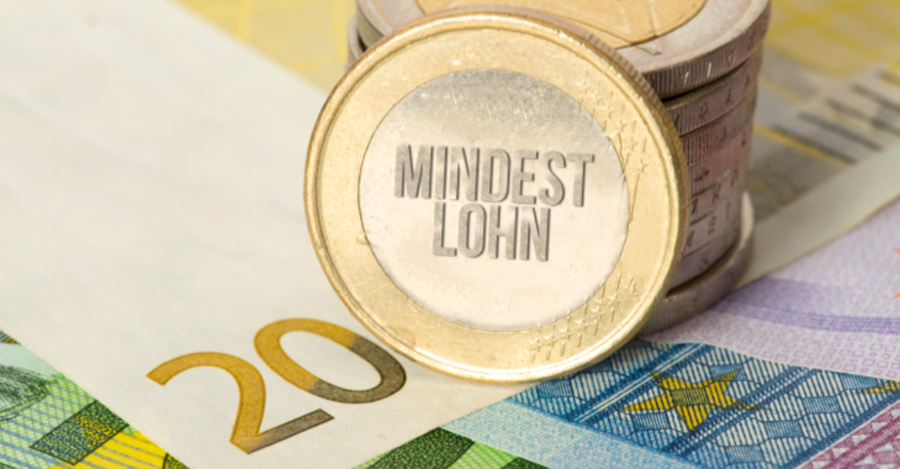 An einen Stapel Euro-Münzen ist eine gangelehnt mit der Aufschrift Mindestlohn © iStock/Stadtratte