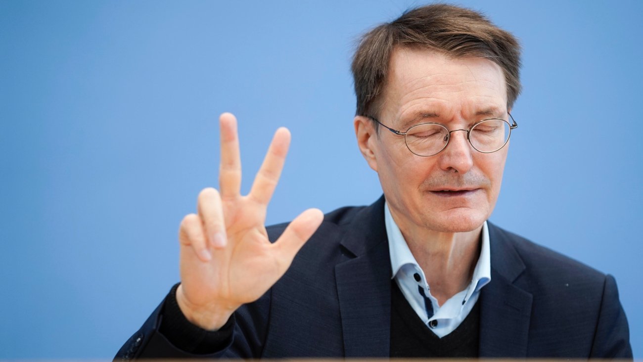 Bundesgesundheitsminister Karl Lauterbach mit geschlossenen Augen spreizt drei Finger der rechten Hand © picture alliance/Flashpic|Jens Krick