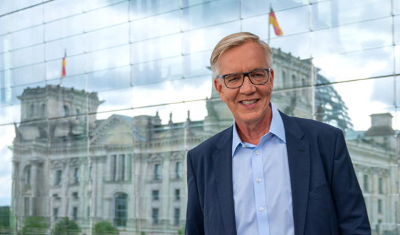 Dietmar Bartsch vor einer Glaswand, in der sich der Reichstag spiegelt © picture alliance/dpa | Christophe Gateau