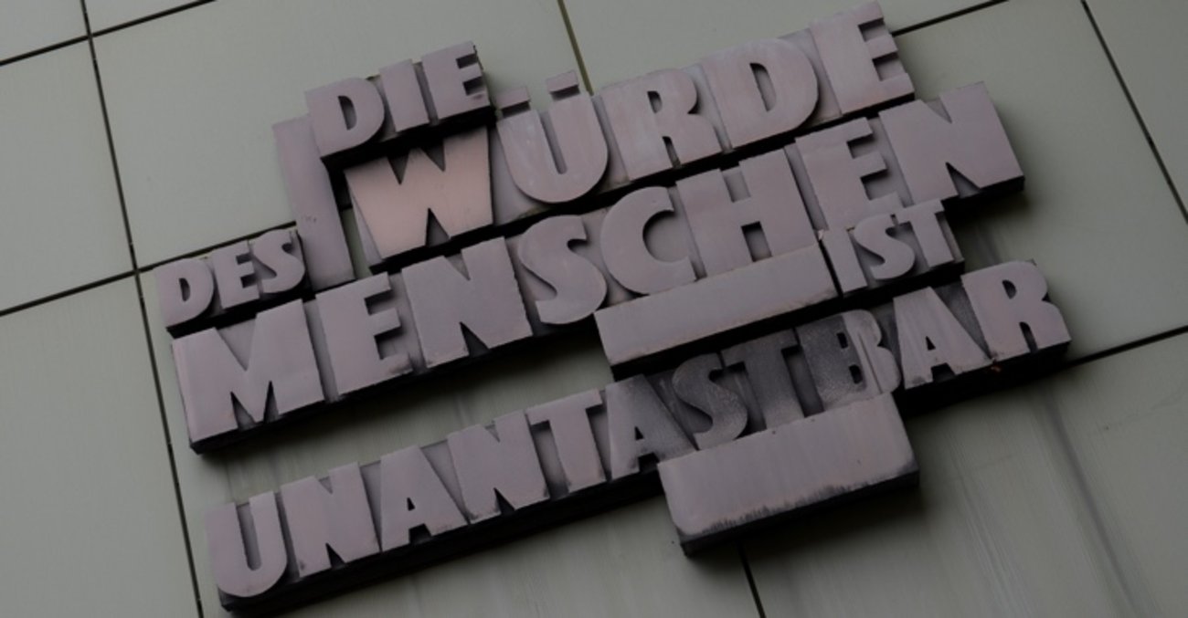 Das Grundgesetz-Zitat "Die Würde des Menschen ist unantastbar" an der Fassade eines Gerichtsgebäudes in Frankfurt am Main  © Arne Dedert/dpa