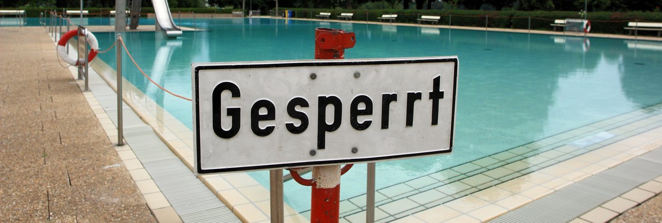 Vor einem Schwimmbecken eines Freibades steht ein Schild mit der Aufschrift Gesperrt © picture alliance/JOKER