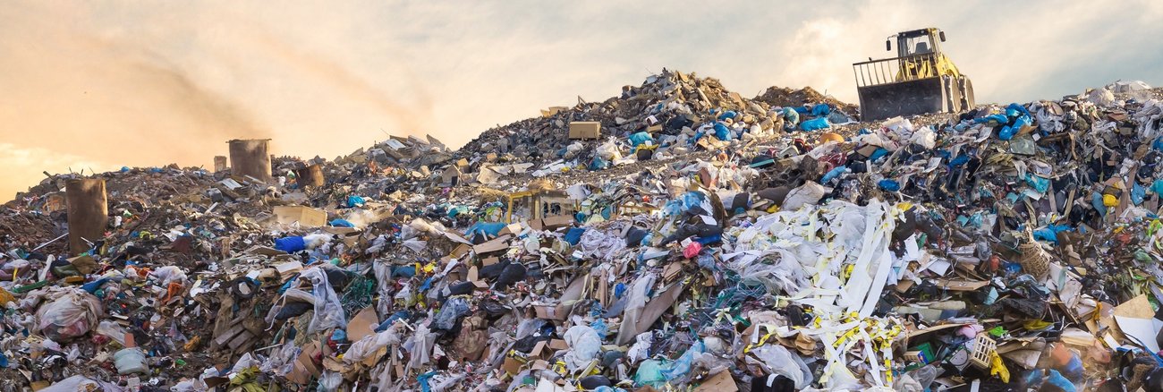 Eine Planierraupe auf einer riesigen Mülldeponie © iStock/vchal
