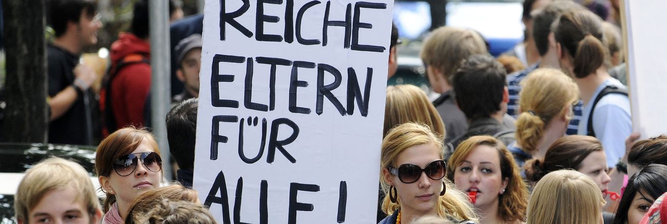 »Reiche Eltern für alle« fordern zwei Protestierende auf ihrem Schild © HenningKaiser/ddp