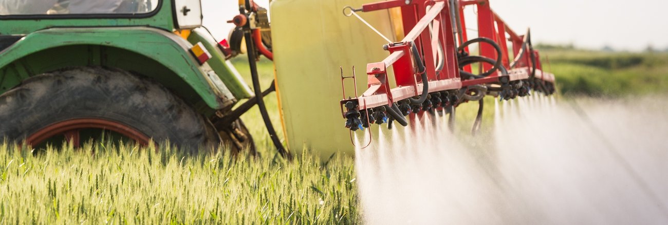 Ein Traktor versprüht Unkrautvernichtungsmittel auf einem Getreidefeld © iStockphoto.com/fotokostic