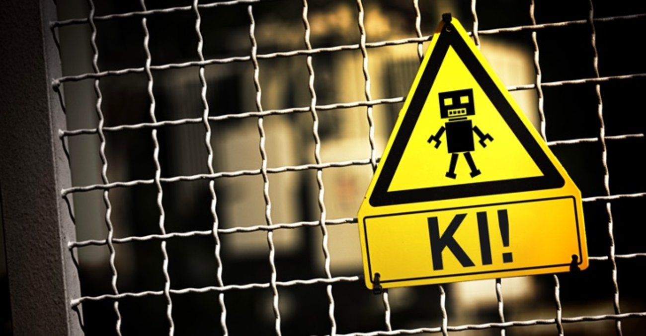 Künstliche Intelligenz: Ein Warnschild an einem Zaun zeigt einen stilisierten Roboter, darunter die Aufschrift: KI! © picture alliance/CHROMORANGE|Christian Ohde