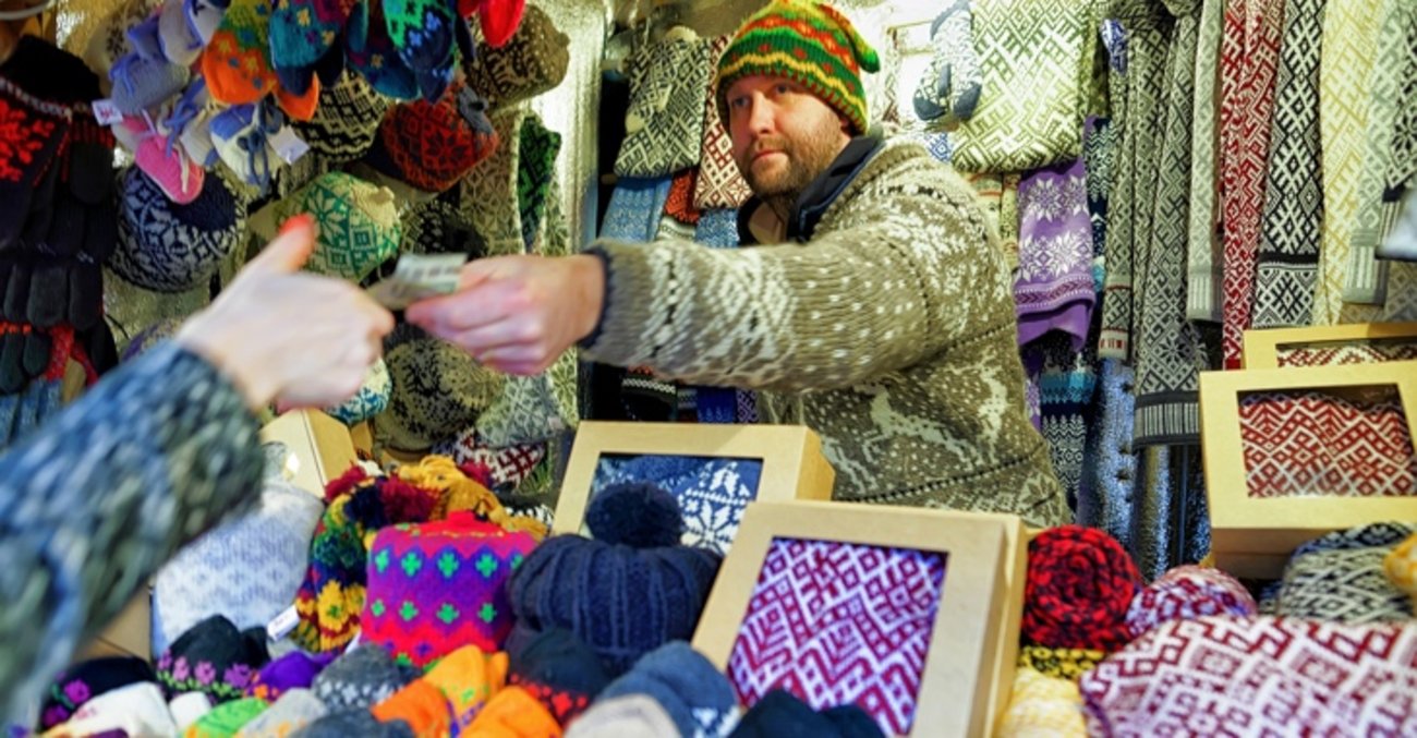 Marktverkäufer mit Strickwaren reicht einer Frau einen Euro-Schein © iStockphoto.com/Roman Babakin