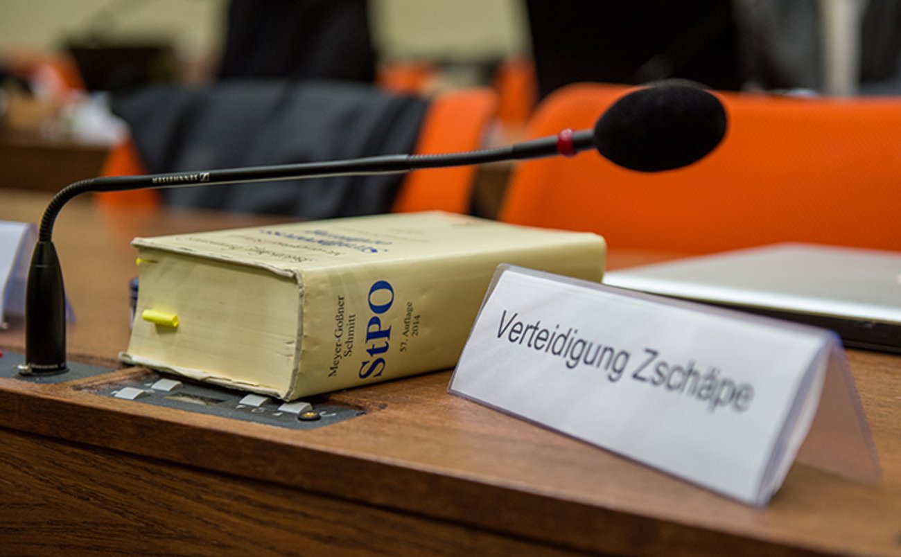 Ein Schild mit der Aufschrift "Verteidigung Zschäpe" steht am 03.12.2014 im Gerichtssaal des Oberlandesgerichts in München (Bayern) neben einer Strafprozessordnung. | Foto: © picture alliance / dpa / Marc Müller
