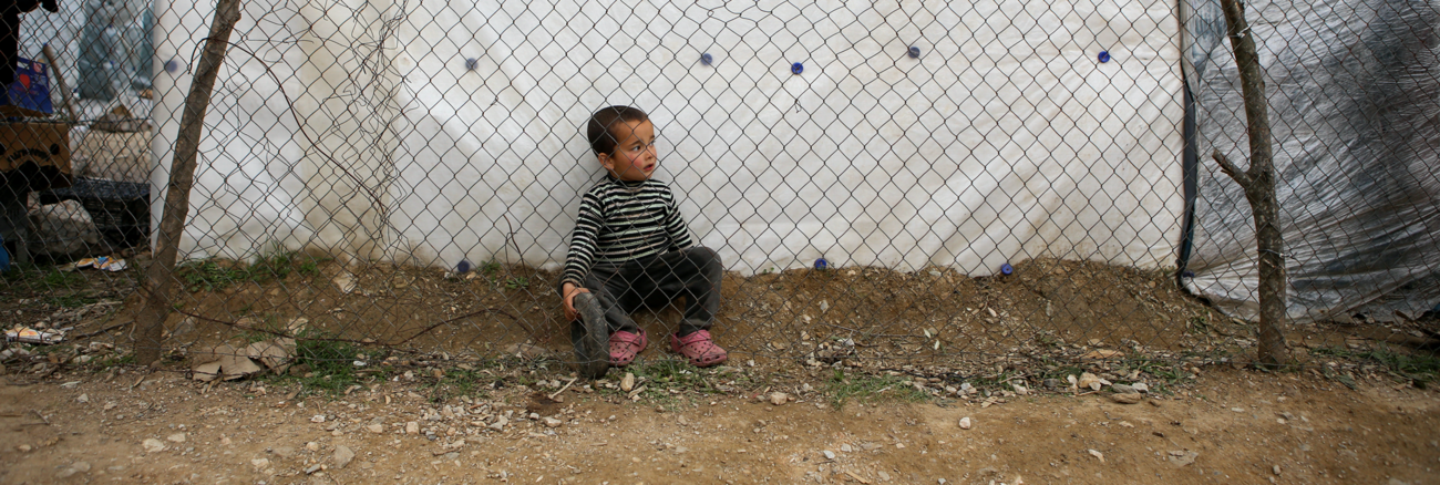 Ein Flüchtlingsjunge sitzt hinter einem Gitterzaun im Lager Moria auf der griechischen Insel Lesbos © REUTERS/Elias Marcou