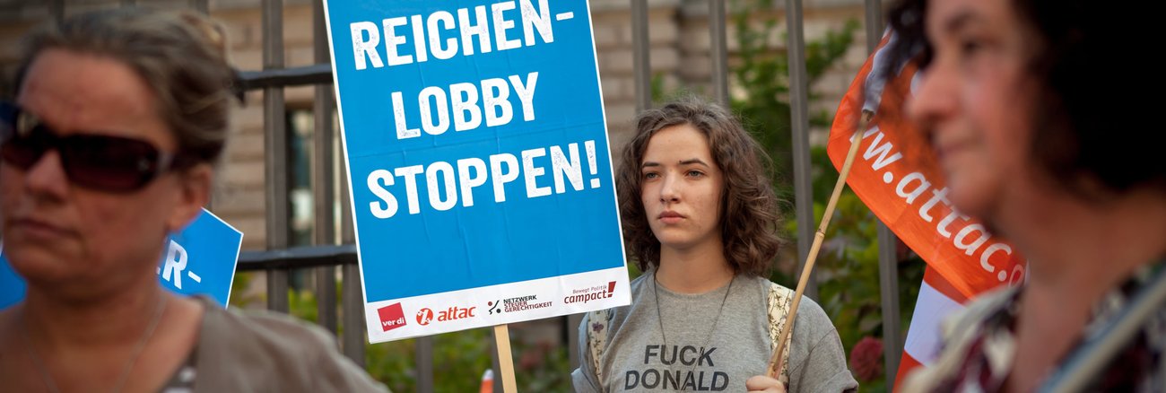 Bei einer Campact-Aktion gegen die von der Bundesregierung geplante Erbschaftsteuerreform hält eine Teilnehmerin ein Schild mit der Aufschrift »Reichenlobby stoppen!« © Jakob Huber/Campact