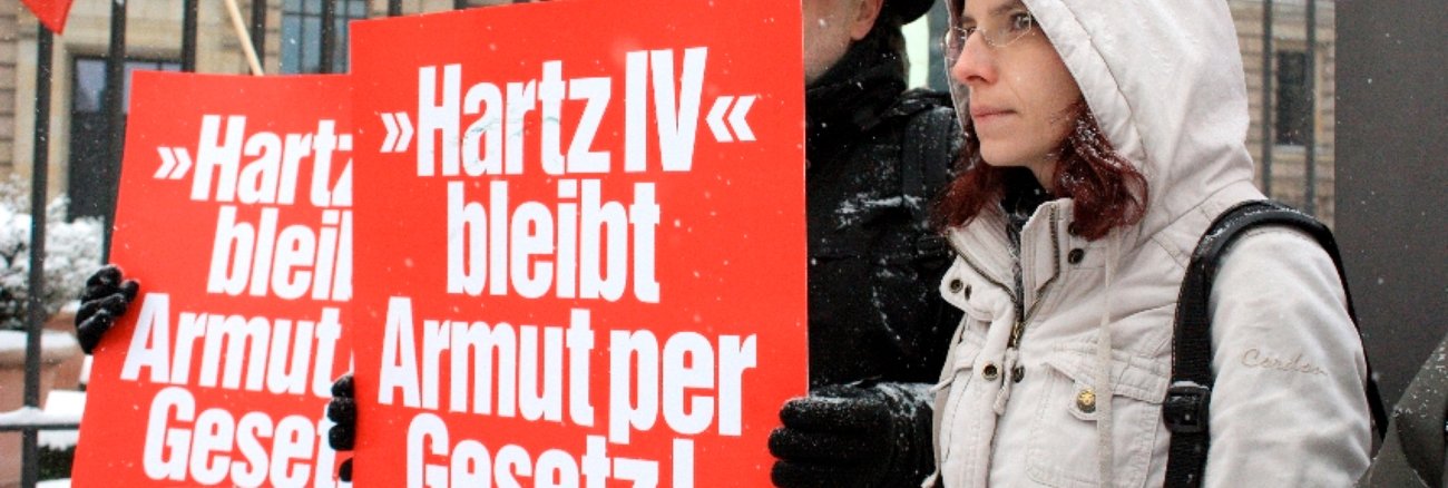 Teilnehmer bei Protesten vor dem Bundesrat halten Schilder mit der Aufschrift: Hartz IV bleibt Armut per Gesetz!
