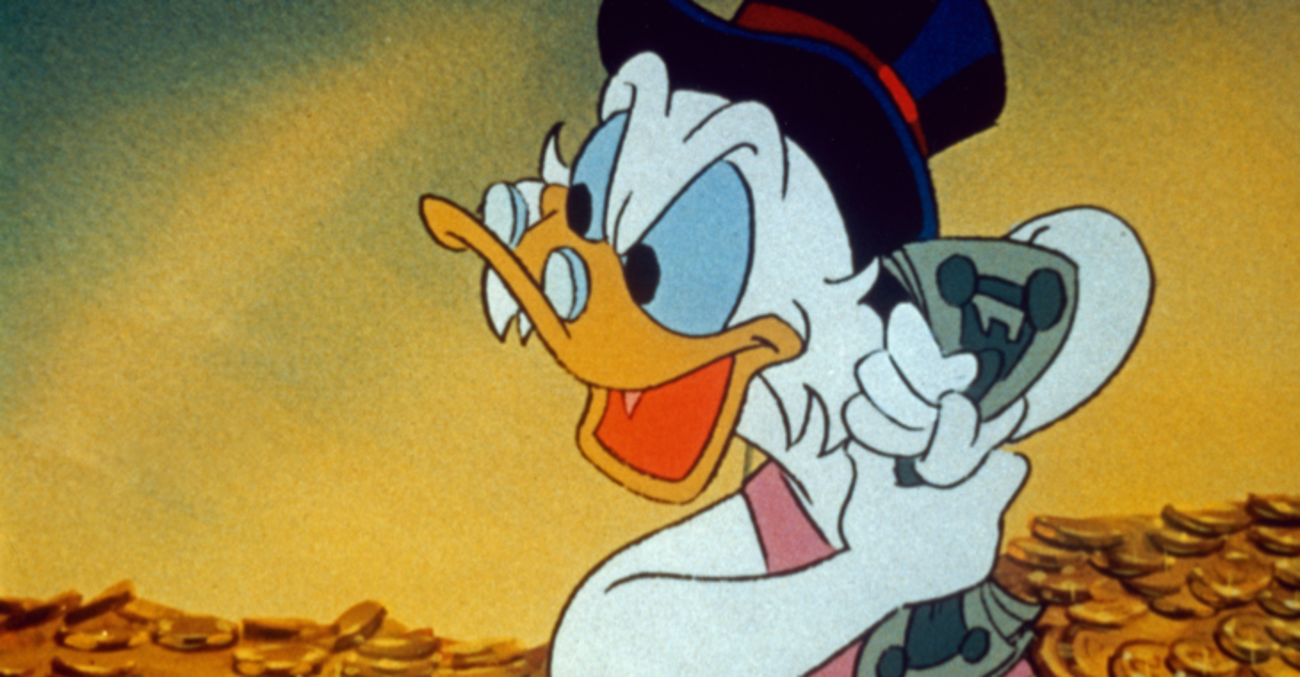 Die Disney-Figur Dagobert Duck mit Geldscheinen in einem Haufen Goldmünzen © picture alliance/United Archives