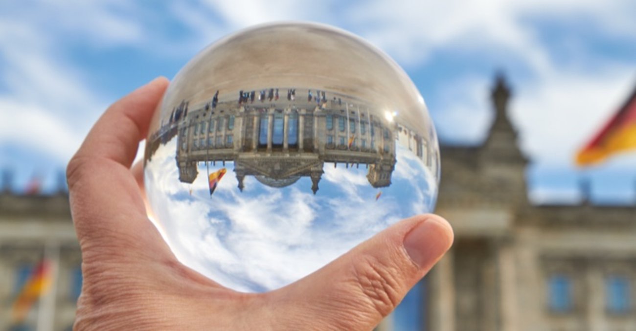 Das Reichstagsgebäude in Berlin durch eine Glaskugel betrachtet auf dem Kopf © iStock/foto-ruhrgebiet
