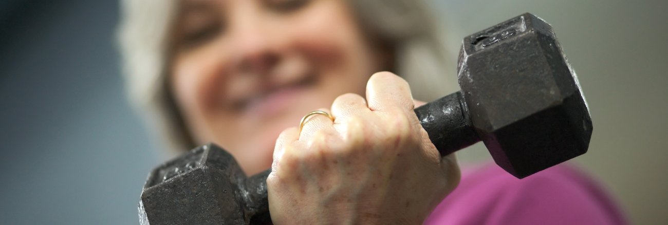 Eine ältere Frau mit grauen Haaren hält eine Hantel © iStock/wbritten