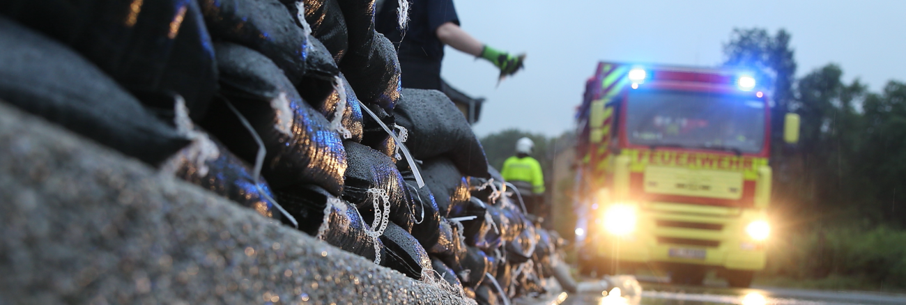 Einsatzkräfte der Feuerwehr errichten am Straßenrand eine Wassersperre aus Sandsäcken © picture alliance/Flashpic/Jens Krick