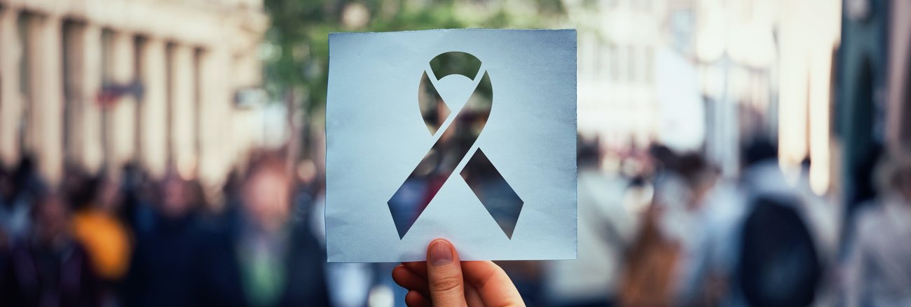 Verschwommene Menschengruppe hinter einer Red Ribbon-Schablone @iStock/Bulat Silvia