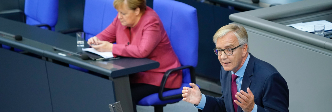 Bundeskanzlerin Merkel auf der Regierungsbank tippt auf ihr Handy, während Dietmar Bartsch am Rednerpult spricht © picture alliance/Flashpic/Jens Krick